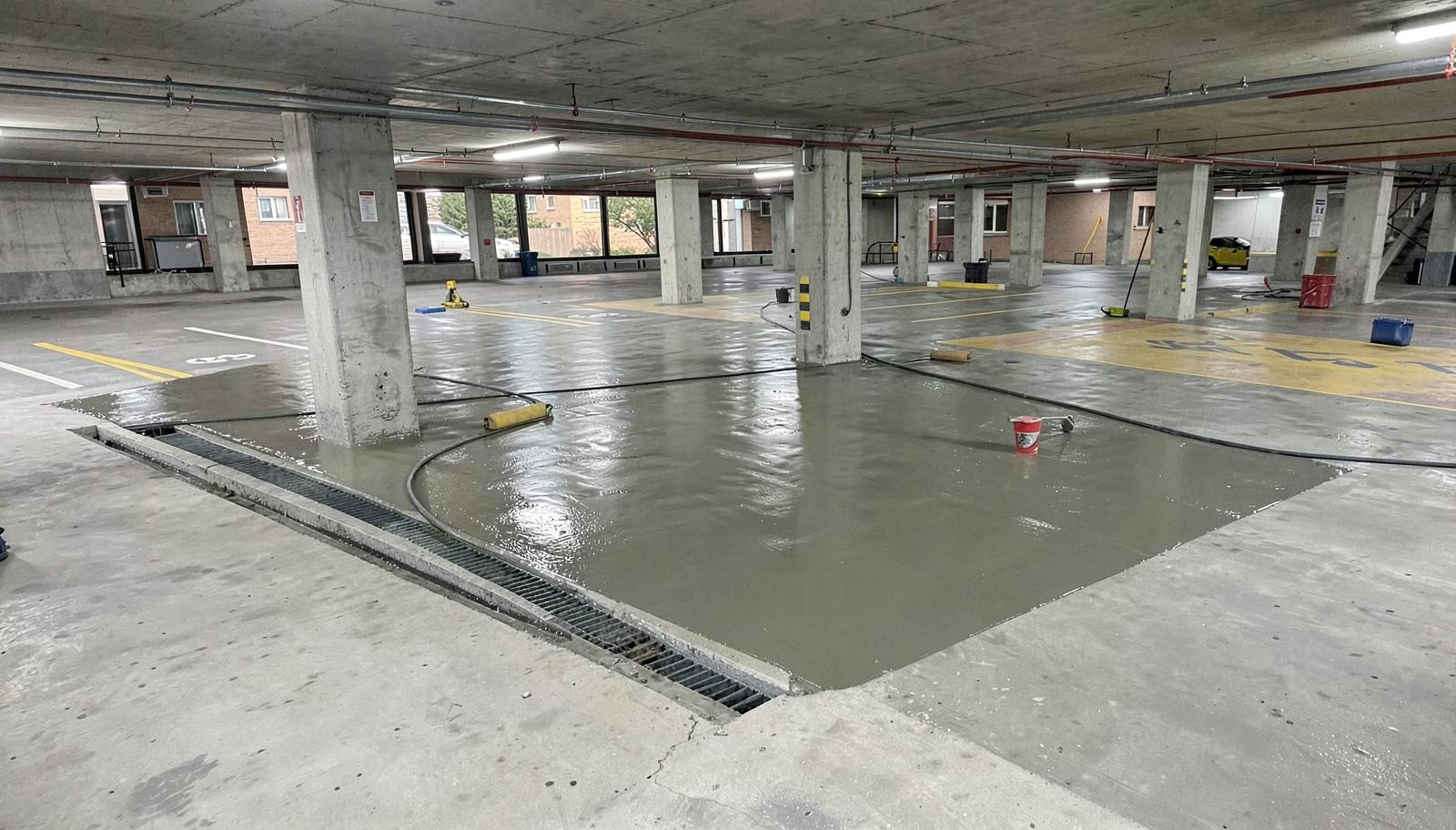 Aplicação de manta líquida de impermeabilização sobre piso de concreto de garagem de condomínio, com ralo e pilares